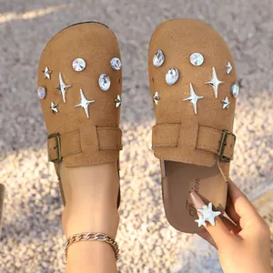 Close-up detail of tan suede clogs featuring sparkling star charms and rhinestones
