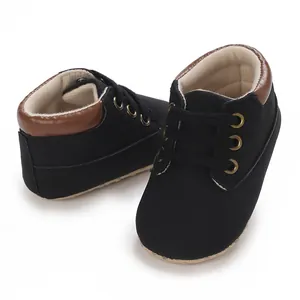 Detail of black baby boy walking shoes with soft soles, brown trim, and lace-up design.