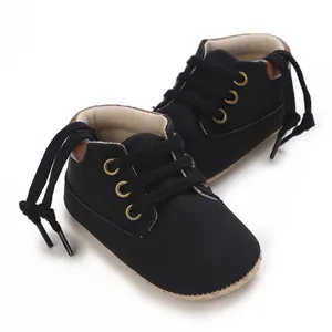 Detail showing soft black infant walking shoes with golden eyelets for baby boys