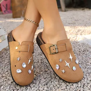 Close-up of tan suede clogs decorated with silver stars and colorful iridescent rhinestones