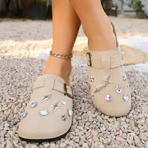 Detail view of beige clogs with decorative star studs and iridescent rhinestones.