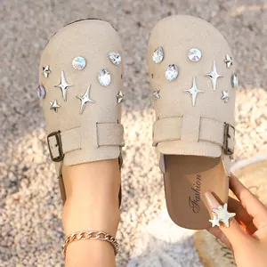 Detail view of beige suede clogs featuring star studs and sparkling crystal embellishments
