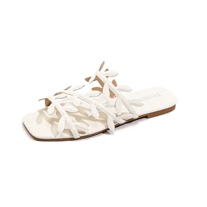 White flat sandals for women featuring unique decorative leaf straps for beach and vacation.