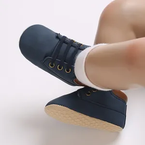 Close-up of navy blue PU leather baby walking shoes with soft soles on infant's feet.