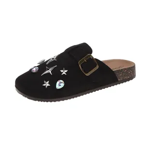Close-up of black suede clogs featuring metallic stars and iridescent gemstone embellishments.
