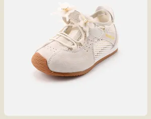 Detail of off-white girls' sneakers featuring elegant flower and pearl decorations on mesh.