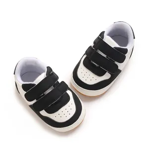 Detail of black and white infant sneakers with dual velcro straps and soft sole