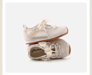 Detailed view of cream girls shoes with delicate 3D floral and pearl decorations.