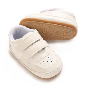 Detailed view of white baby walking shoes with soft non-slip rubber soles and velcro straps.