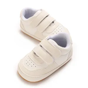 Close-up of white infant walking shoes with double hook-and-loop straps and soft soles.