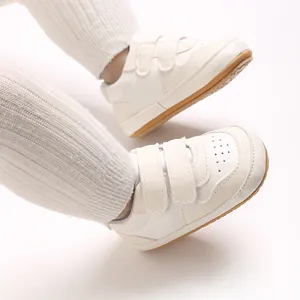 Detail view of white infant walking shoes with soft non-slip rubber soles and velcro straps