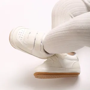 Detail of white baby walking shoes with soft rubber sole and hook-and-loop straps