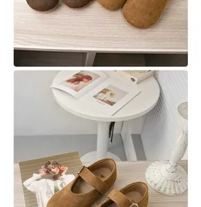 Makroansicht von braunen Wildleder-Kinderschuhen im Mary-Jane-Stil auf einem Holztisch.
