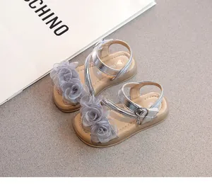 Détail montrant des sandales argentées pour filles avec fleurs en résille grise.