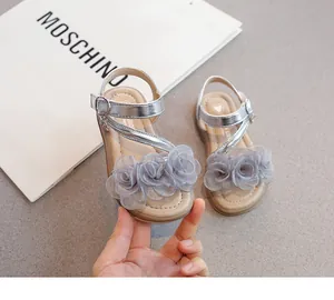 Détail de sandales argentées pour filles avec des décorations de roses en tissu gris