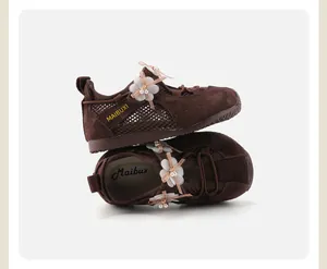 Detail of brown girl's mesh sneakers featuring floral pearl accents and soft soles.