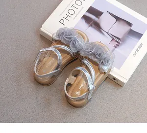 Détail de sandales argentées pour filles avec fleurs en tulle 3D et semelles souples.