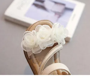 Nahaufnahme eleganter Organza-Blumen und Strassriemen an Sandalen für Kleinkinder