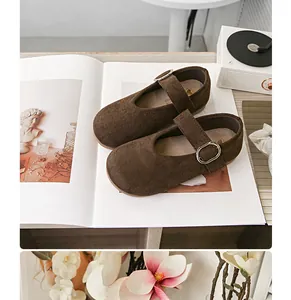 Nahaufnahme braune Wildleder-Mary-Jane-Kinderschuhe mit silberner Schnalle auf Magazin.