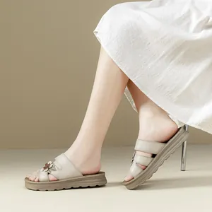 Sandalias de plataforma de cuero suave con flores, lucidas por una modelo con falda blanca.
