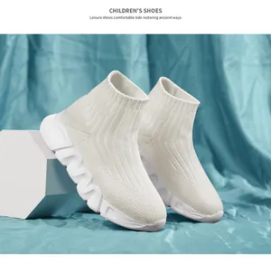Detalle de zapatillas tipo calcetín de punto blanco para niños con suela gruesa ondulada