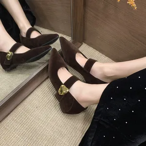 Nahaufnahme brauner Mary Jane Schuhe aus Wildleder mit modischer goldener Herzschnalle