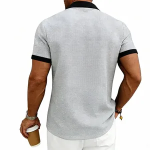 Vue détaillée montrant la coupe arrière et la texture gaufrée d'un polo gris à bord noir.