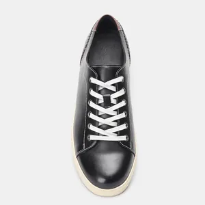 Draufsicht auf klassische schwarze Herren-Sneaker mit weißen Schnürsenkeln und Sohlen