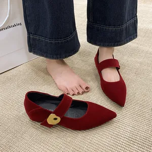 Detailaufnahme von roten Mary Jane Schuhen aus Wildleder mit einer goldener Herzschnalle.