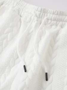 Detailopname van de complexe witte jacquard gebreide textuur op deze herensportbroek