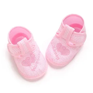 Vue de dessus de chaussures bébé à rayures roses avec broderie coeur et semelles souples