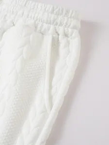 Macro detail van witte jacquard gebreide stof met kabelpatroon op casual shorts