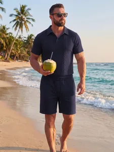 Marineblauw jacquard gebreid heren zomershirt en short op een tropisch strand decor.