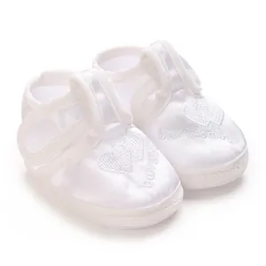 Gros plan détaillé de chaussures de baptême blanches pour bébés avec broderie en cœur