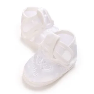 Vue détaillée des chaussures de baptême blanches pour bébé avec broderie de cœur et satin