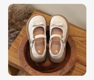 Vista dall'alto di scarpe Mary Jane crema per bambine con elegante fiocco in pelle.