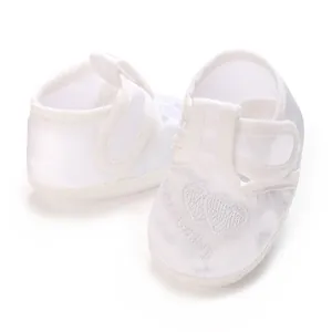 Gros plan de chaussures de baptême blanches pour bébé avec broderie cœur