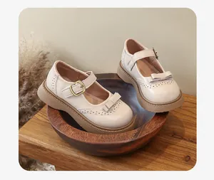 Eleganti scarpe Mary Jane in pelle beige per bambine con fiocco e suola spessa.