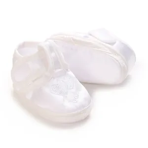 Gros plan de chaussures de baptême en satin blanc pour bébé avec broderie cœur et semelle