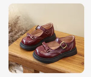 Vista dettagliata delle scarpe Mary Jane bordeaux con fiocco su una panca di legno