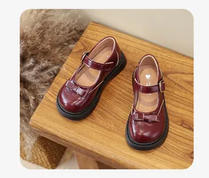 Dettaglio di scarpe Mary Jane bordeaux da bambina con fiocco classico e cinturino.