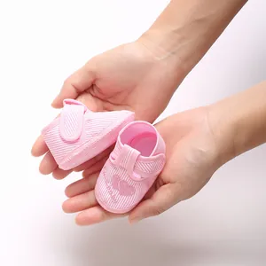 Détail rapproché de chaussures bébé à rayures roses avec semelle souple et broderie cœur