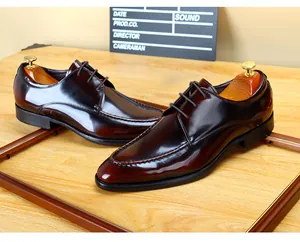 Detailed shot of glossy burgundy patent leather men's dress shoes on wooden surface