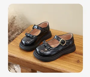 Classiche scarpe Mary Jane nere da bambina con fiocco e fibbia su una panca di legno