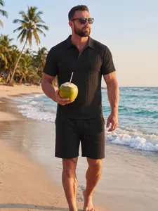 Model met een zwarte jacquard gebreide polo en shortset op een tropisch strand