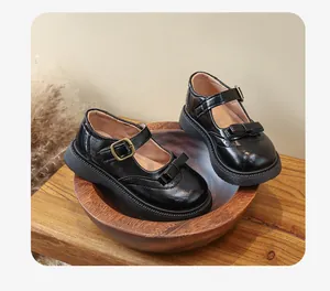 Primo piano di scarpe Mary Jane nere da bambina con fiocchi e fibbie dorate