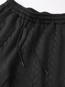 Detail van zwarte jacquardstof en elastische tailleband met trekkoord voor heren.