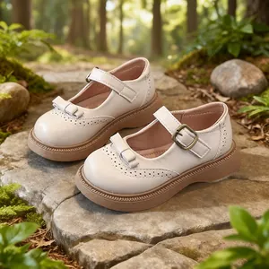 Scarpe Mary Jane bianche per bambina con fiocco e spessa suola marrone con zeppa all'aperto.