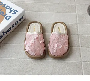 Primer plano de zapatillas de encaje rosa para niña con flores 3D en baldosas grises