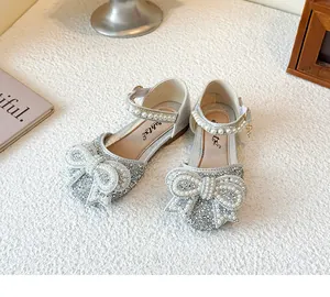 Close-up detail of silver girls' princess shoes featuring a large pearly rhinestone bow